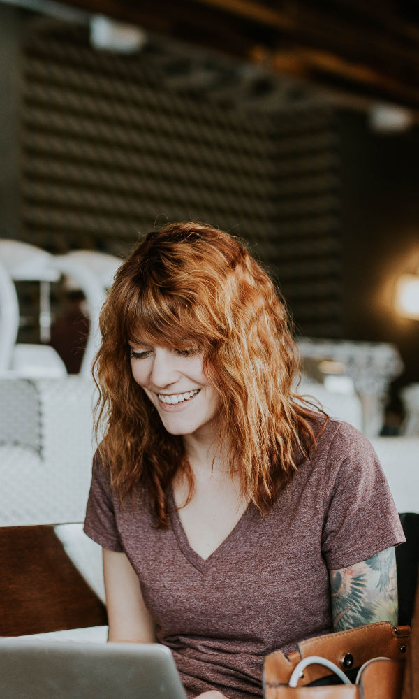Une femme heureuse et souriante sur un ordinateur portable dans un café